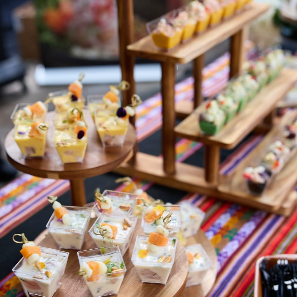 A buffet table with various appetizers in small cups, including ceviche and other colorful dishes.